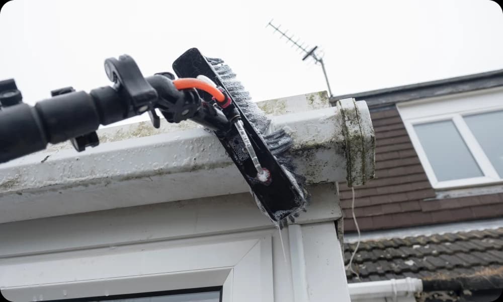 professional gutter cleaner tackling dirty white plastic pvc gutter with specialist brush