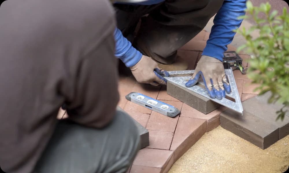 expert measuring a brick paver for patio installation