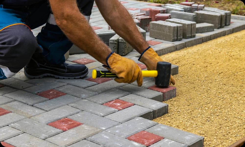 patio installer hammering decorative red slabs in a patio installation