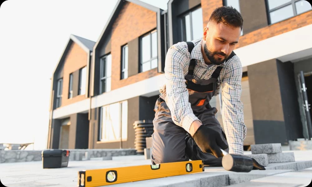 patio layer installing paving stones in front of residential buildings